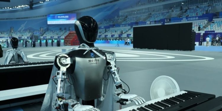 2025世界人形機器人運動會14日至17日在中國國家速滑館「冰絲帶」舉行。圖為機器人彈鋼琴，一旁有電風扇幫機器人降溫。中央社記者謝怡璇北京攝 114年8月14日