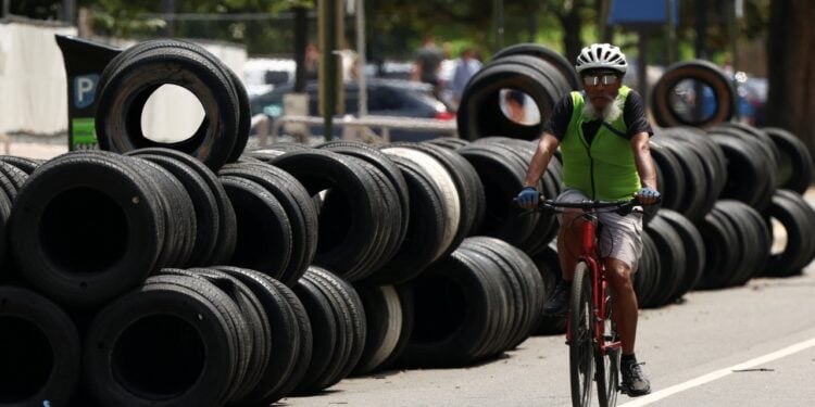 一位自行車騎士騎經廢棄的輪胎區。（REUTERS）